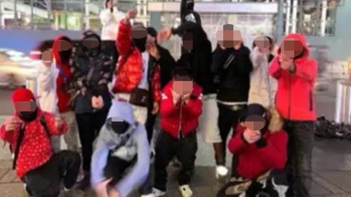 Suspected Tren de Aragua members in masks and hoods, giving the finger to the camera