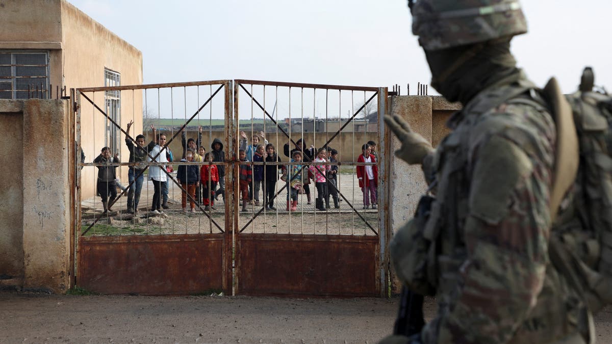 A soldier from the US-led coalition gestures towards schoolchildren during a joint U.S.- Kurdish-led Syrian Democratic Forces (SDF) patrol in the countryside of Qamishli in northeastern Syria Feb. 8, 2024.