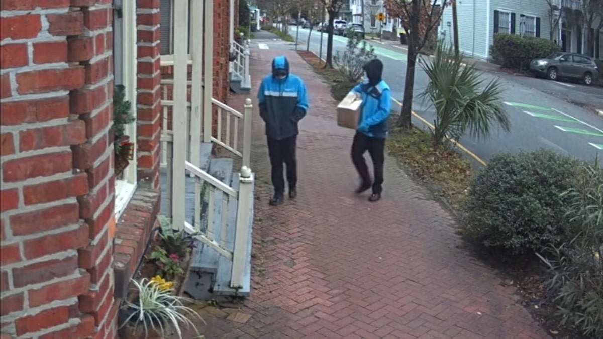 The two men disguised as Amazon workers approaching Hardison's door