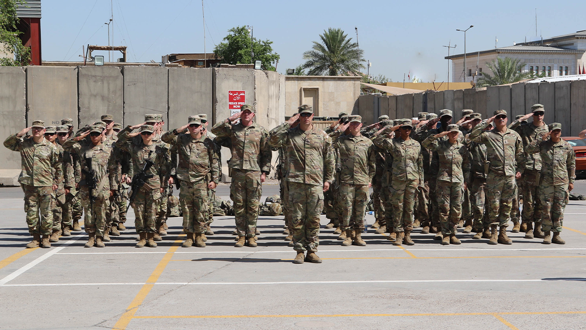 Service members part of Operation Inherent Resolve stand in formation and salute the United States flag during a Memorial Day ceremony at Union III in Baghdad on May 27, 2024.