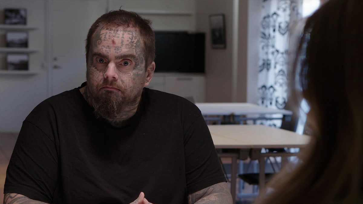 Isakin Jonsson wearing a black shirt and sitting in front of his daughter looking at the camera.