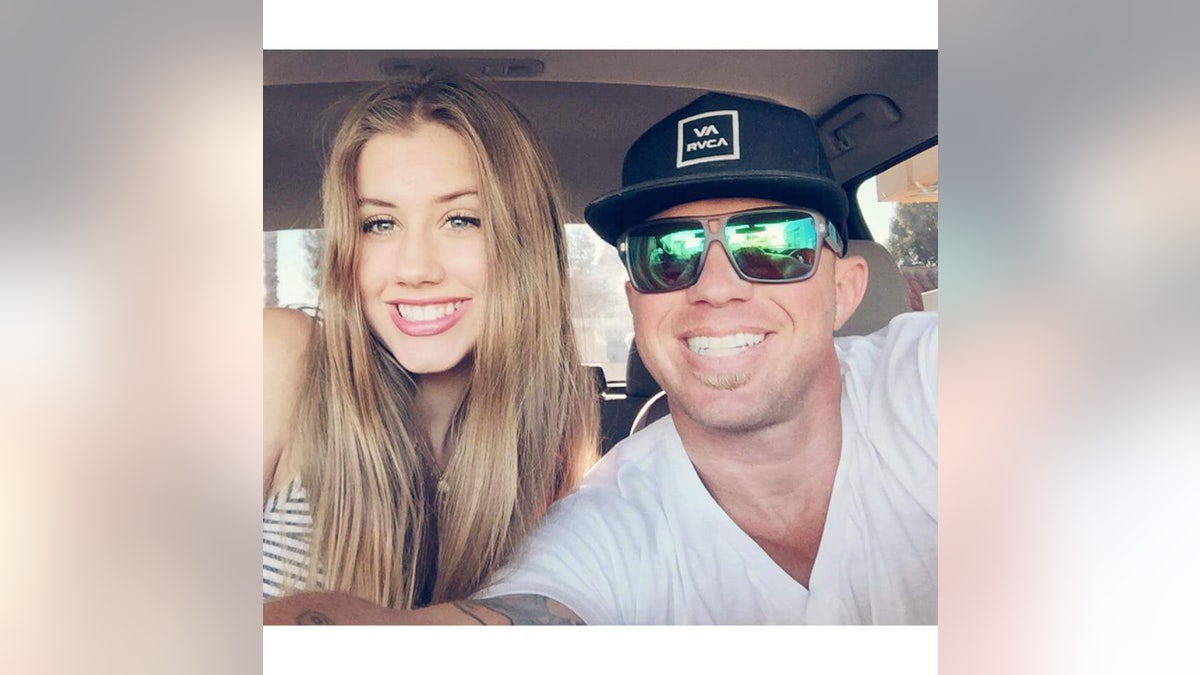 James Kulstad wearing a white shirt and sunglasses posing with a hat inside a car with a smiling woman.