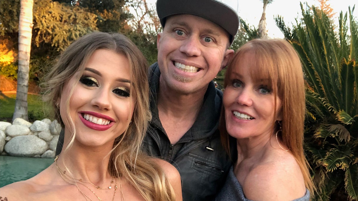 James Kulstad smiling and posing with his mother and another woman.