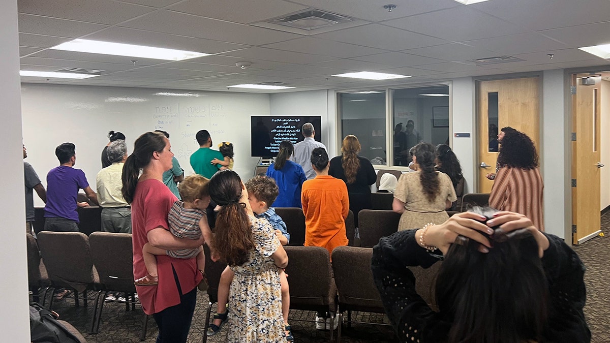 Congregants at an Afghan Christian church in Oklahoma City worship with lyrics in Dari projected on a screen during a Sunday service