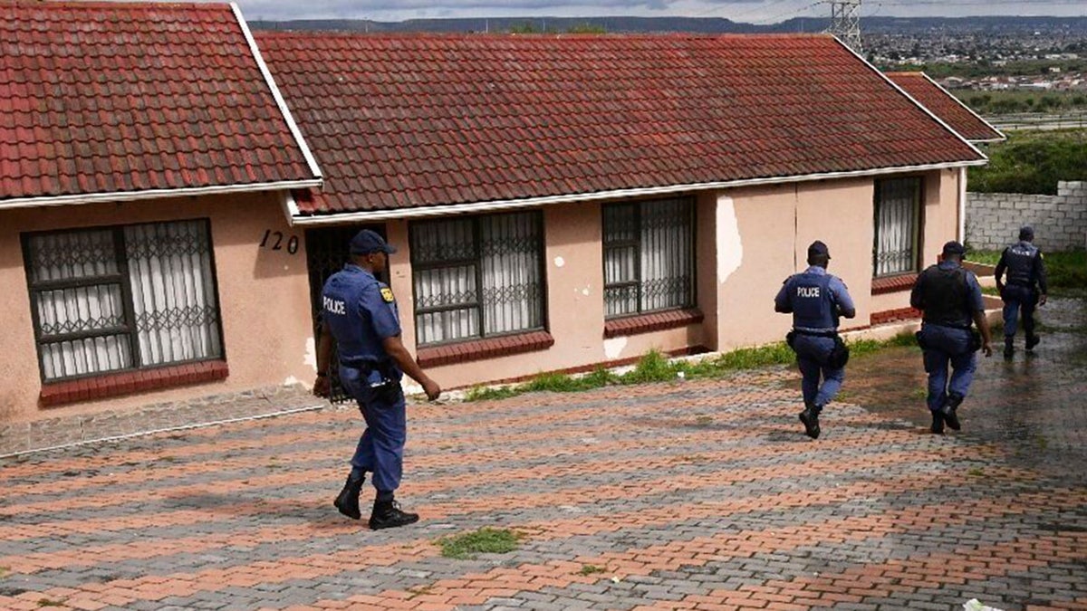 South Africa officials walk outside a house