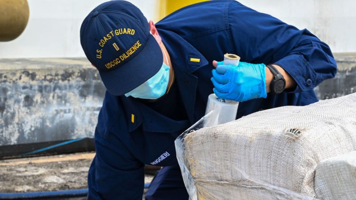 A Coast Guard member seen wrapping bails of illegal drugs on a ship
