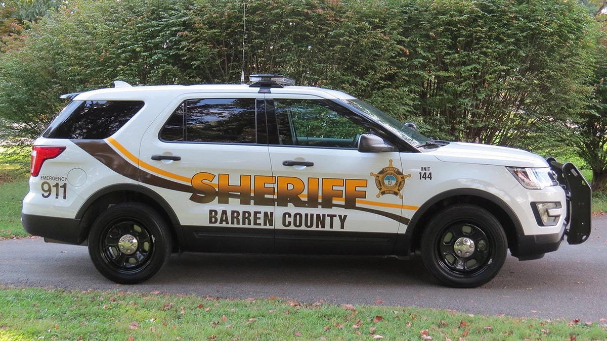 A white Barren County Sheriff's Office vehicle parked in front of a green hedge
