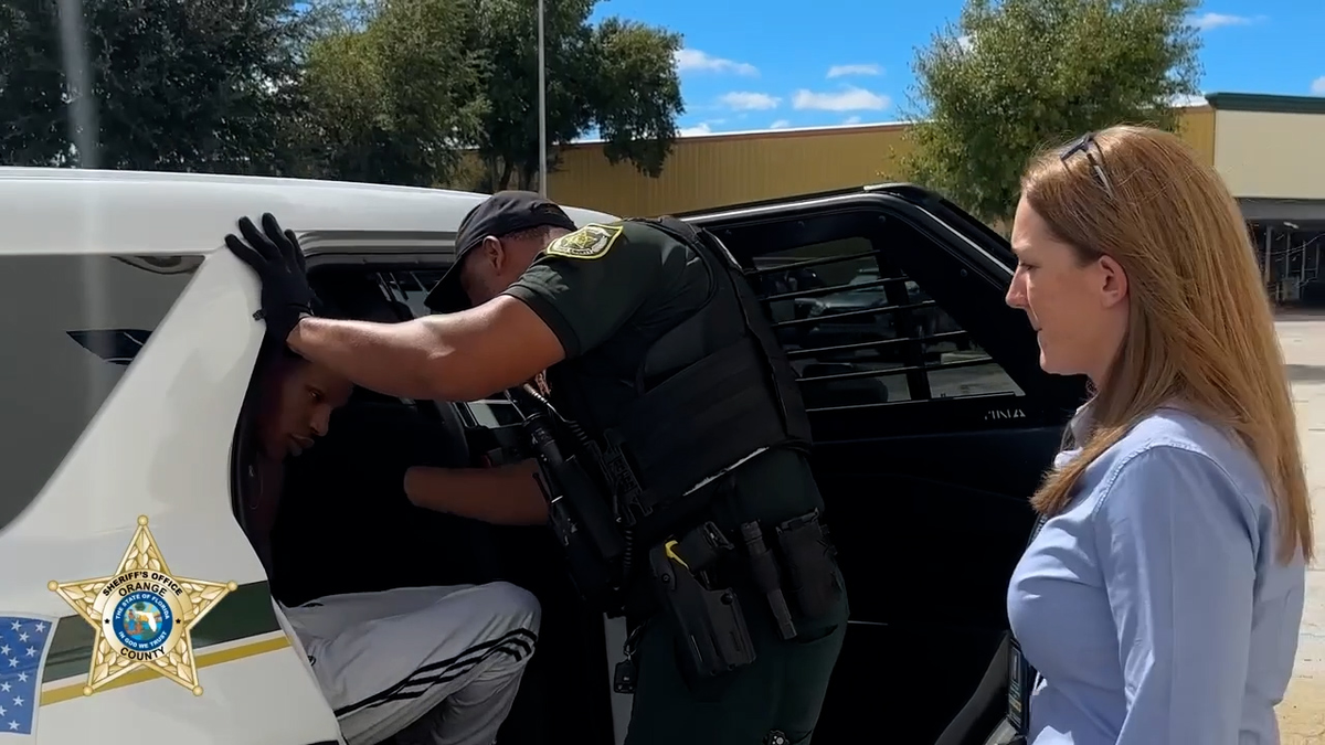 Tillman seated in the back of a patrol SUV