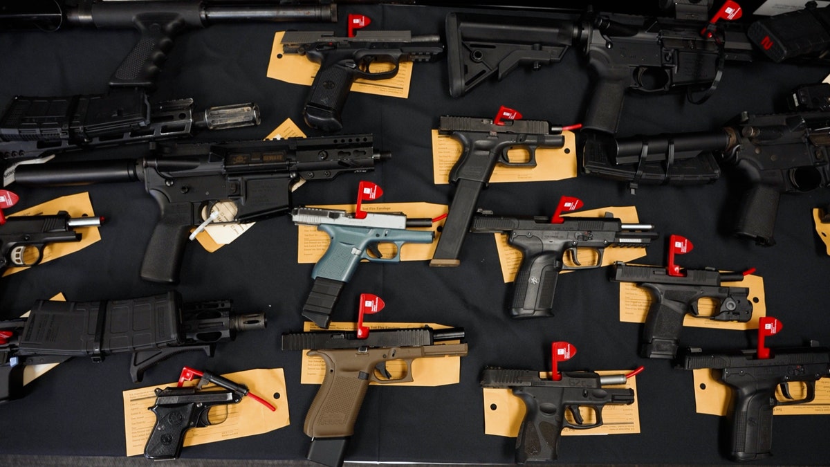 seized pistols and rifles laid out on a table with tags