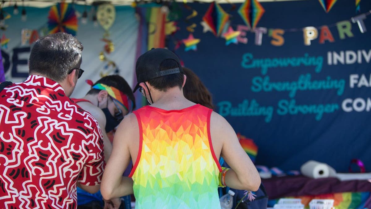 People wearing colorful clothing gather at a booth during the Phoenix Pride Festival in 2023.