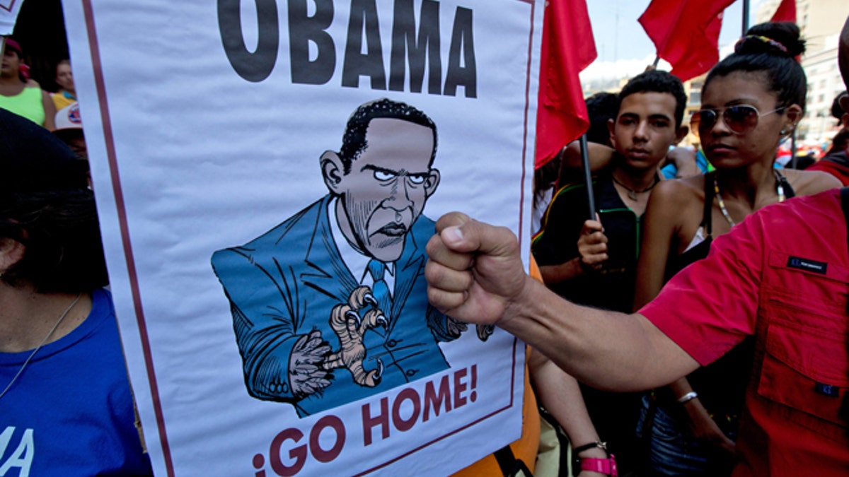 A man holds his fist next to a poster depicting President Barack Obama, during an anti-U.S. rally, in Caracas, Venezuela, Saturday, March 12, 2016. President Nicolas Maduro called back Venezuela's top diplomat in Washington, protesting the renewal of sanctions by Obama on several of Venezuela's top officials over human rights violations. The two nations haven't exchanged ambassadors since 2010. (AP Photo/Fernando Llano)