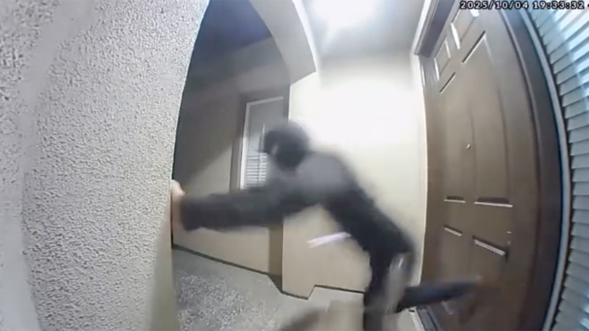 A masked individual kicks the front door of a California home