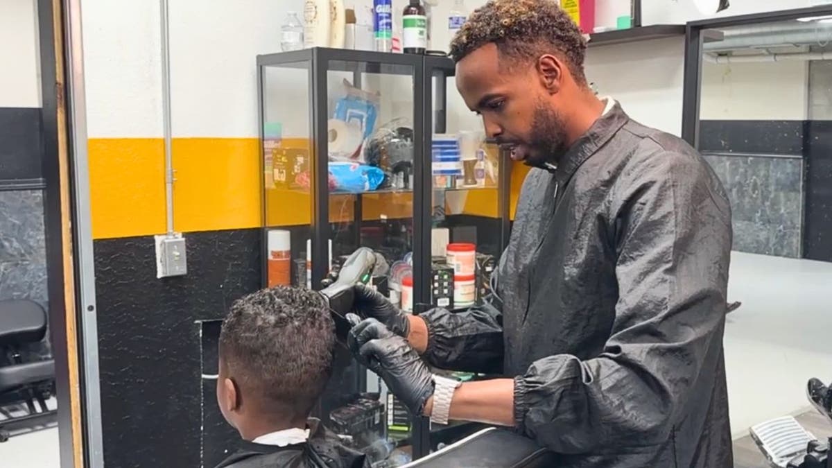 Barber Mahmoud Hussain cutting hair in Minneapolis-area mall shop