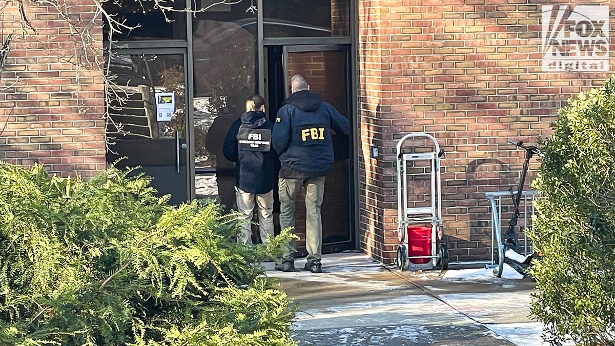 FBI agents in jackets entering door of building.