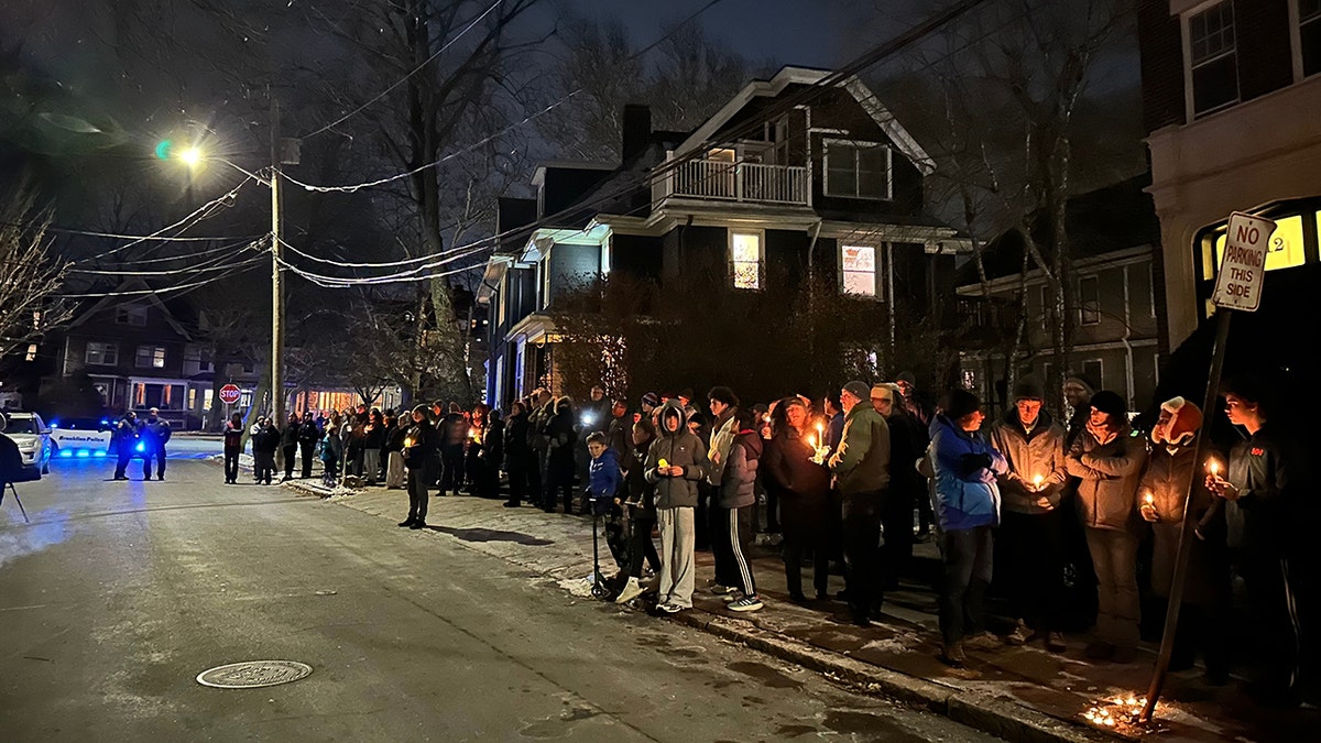 A crowd of people holding candles gather outside the home of slain MIT professor Nuno Loureiro