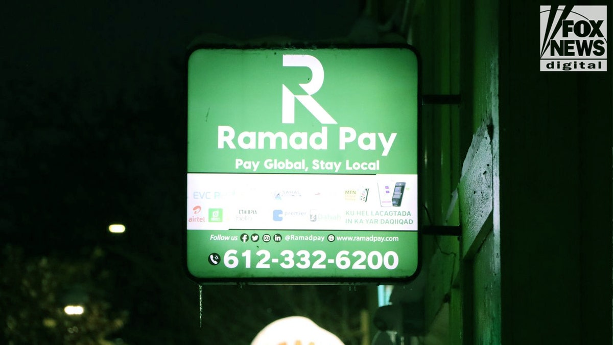 Ramad Pay money-transfer sign glowing green at night in Minneapolis.