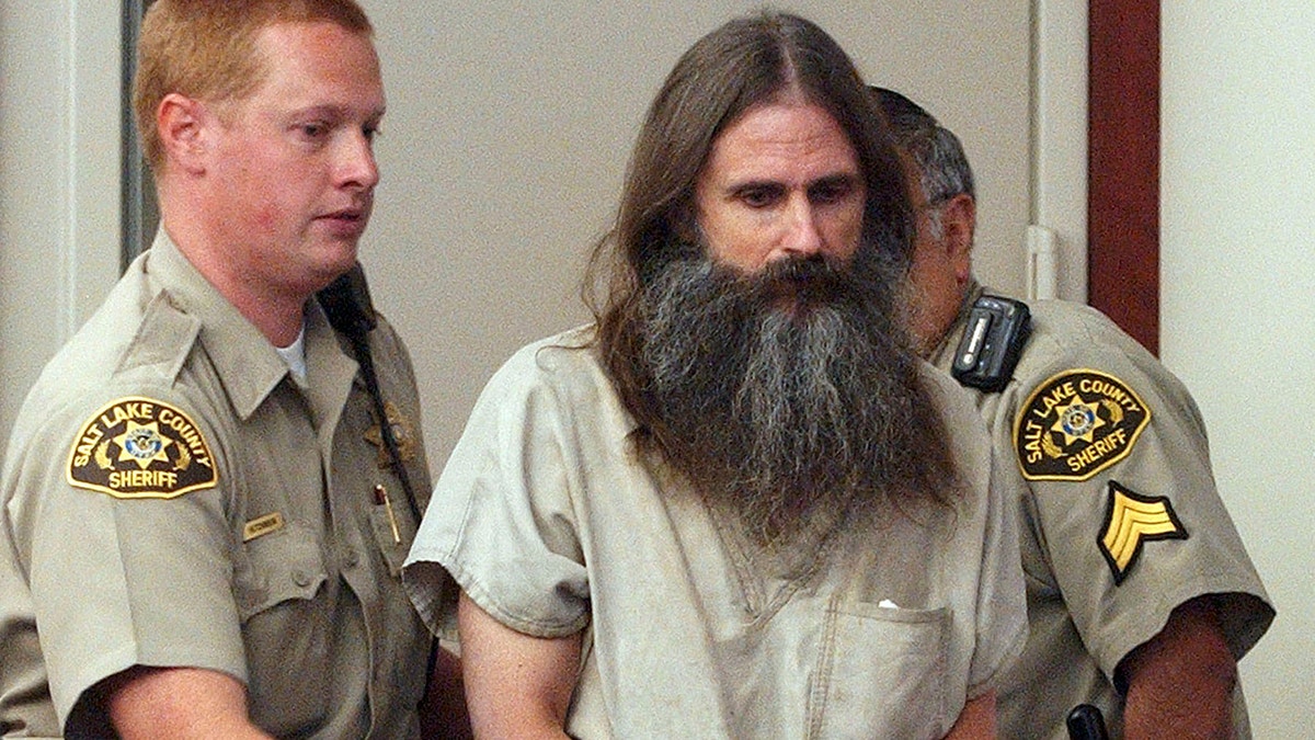 Brian David Mitchell in handcuffs being escorted by police.