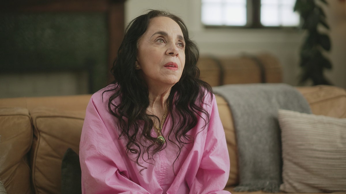 Laura Greenberg looking up in a bubblegum pink blouse.