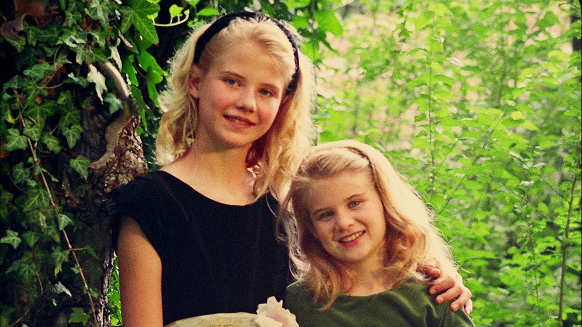 A young Elizabeth Smart holding onto her sister in a family portrait.