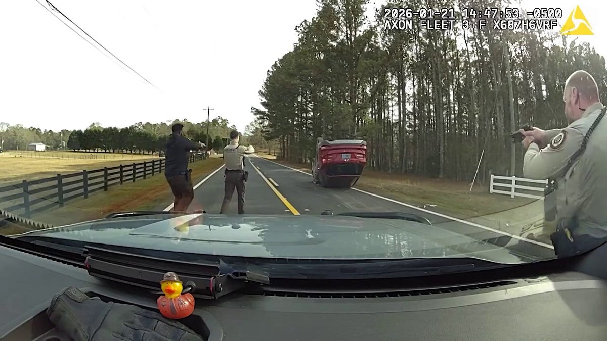 Sheriff deputies surround a red SUV following a rollover crash.