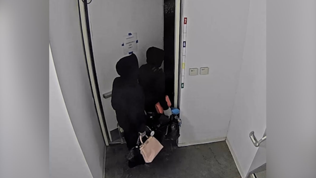 Suspects wearing hoodies carry handbags inside office building