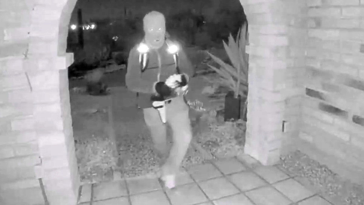 A view from a doorbell camera showing an armed individual outside the residence of Nancy Guthrie in Tucson, Arizona