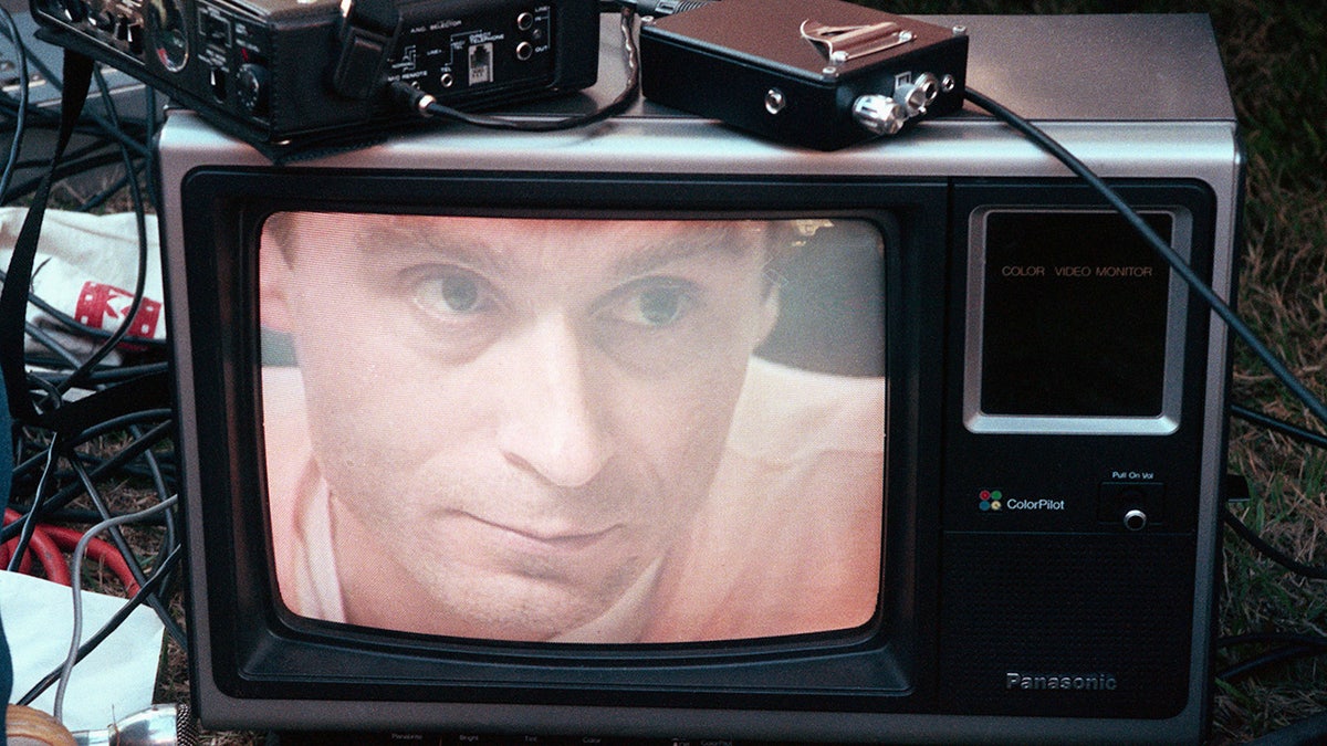 Ted Bundy is seen here on a screen in an orange jumpsuit.