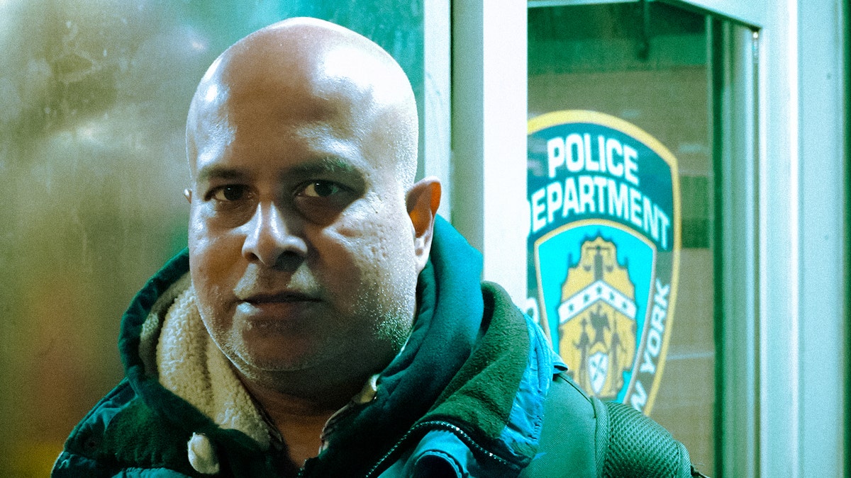 Close up of man standing next to NYC police department sign in background