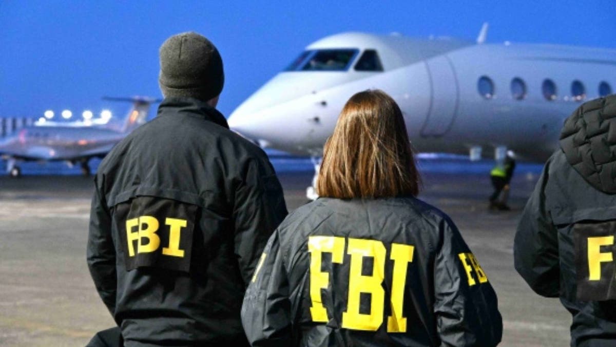 FBI agents standing on an airport tarmac near a private jet at night.