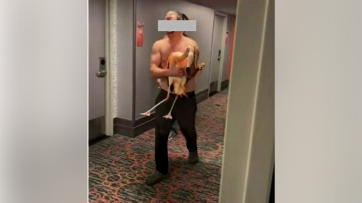 A man holding a flamingo in a hallway.